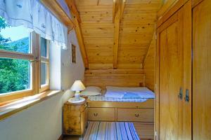 Cama pequeña en habitación de madera con ventana en Osmak in Gusti Laz (Haus für 4 Personen), en Brod na Kupi
