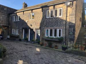 a brick house with potted plants in front of it at Over The Bridge Guest House in Ripponden