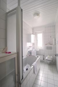 bagno bianco con vasca e servizi igienici di Gästehaus Edith, 4-Sterne für 2 Personen a Trittenheim