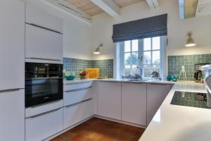 a kitchen with white cabinets and a window at Ferienhaus Lochterbarig in Munkmarsch +4 photos