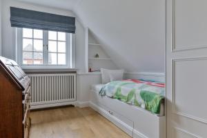 a white bedroom with a bed and a window at Ferienhaus Lochterbarig in Munkmarsch