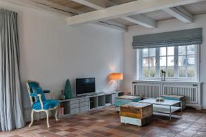a living room with a tv and a blue chair at Ferienhaus Lochterbarig in Munkmarsch