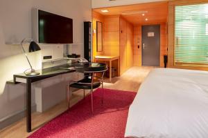 a bedroom with a bed and a desk with a television at Hotel Rival in Stockholm