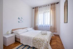 a white bedroom with a bed and a window at Apartment Blaž in Split