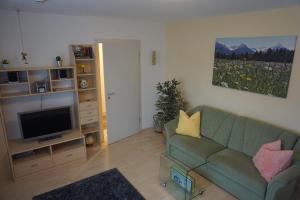 sala de estar con sofá verde y TV en Apartment Regina, en Burgberg