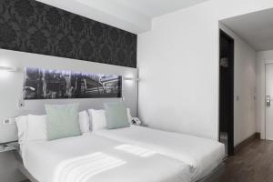 a bedroom with a large white bed with green pillows at Petit Palace Plaza Mayor in Madrid