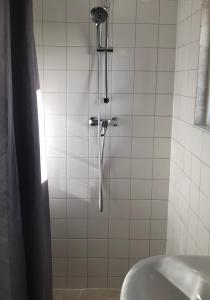 a shower in a white tiled bathroom with a sink at Fila Stroo in Kamperland