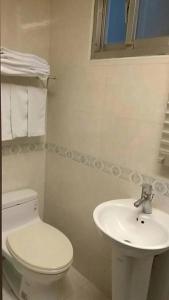 ein weißes Bad mit einem WC und einem Waschbecken in der Unterkunft Meets Happy Hotel in Yonghe