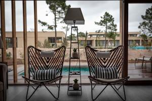 two rocking chairs sitting on a porch with a pool at Pestana Troia Eco-Resort & Residences in Troia