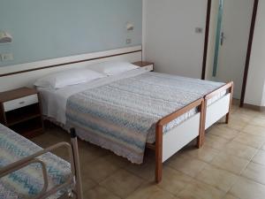 een kleine slaapkamer met een bed en een stoel bij Hotel Lora in Rimini