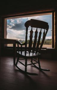 a wooden rocking chair sitting in front of a window at Klanjscek Wine&Stay in Gorizia