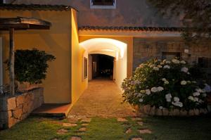 a hallway leading to a house with a flower bush at Hotel Il Piccolo Golf in Porto Cervo