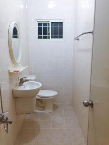 La salle de bains blanche est pourvue de toilettes et d'un lavabo. dans l'établissement Juan Guesthouse, à Pingtung