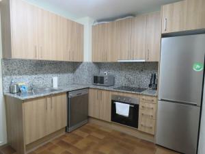 uma cozinha com armários de madeira e um frigorífico de aço inoxidável em SUITEDREAMS-Avet 21 em Andorra-a-Velha