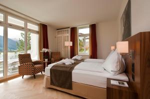 a bedroom with a bed and a large window at Waldhotel & SPA Davos - for body & soul in Davos