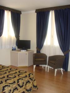 a bedroom with a bed and a tv and curtains at Hotel Belforte in Ovada