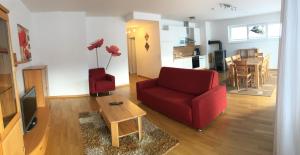 a living room with a red couch and a table at Sonnenalpe Apartments Nassfeld in Sonnenalpe Nassfeld