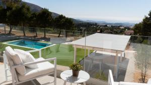 uma varanda com uma mesa e cadeiras e uma piscina em Nature Suites Puig Campana by AR Hotels & Resorts em Finestrat