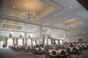 um salão de banquetes com mesas e cadeiras e um lustre em Hillsdale College Dow Hotel and Conference Center em Hillsdale