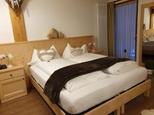 a bedroom with a large bed with white sheets at Hotel Chalet Giasenei in Sagron Mis