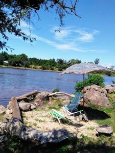 a chair and an umbrella on the shore of a lake at El Chaparral in Potrero de Garay