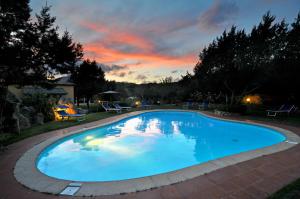 a large blue swimming pool with a sunset in the background at Hotel Il Piccolo Golf in Porto Cervo