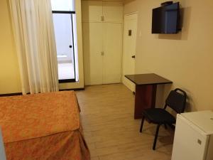 Habitación con cama, escritorio y TV. en Hotel El Brujo Centro Histórico, en Trujillo