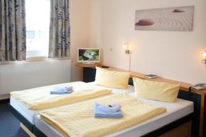 two beds in a hotel room with towels on them at VCH Hotel Greifswald in Greifswald