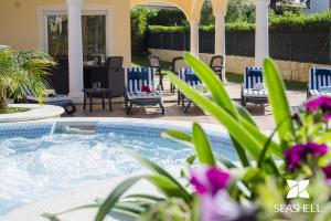 a backyard with a hot tub and chairs and flowers at Villa Hera in Vilamoura