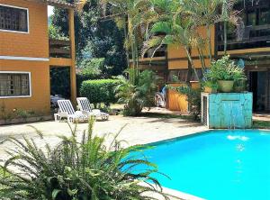 a large blue swimming pool in front of a building at Apartamento em Condomínio Praia de Boiçucanga Litoral Norte in Boicucanga