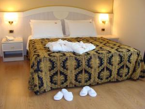 Habitación de hotel con cama con zapatillas en el suelo en Hotel Belforte en Ovada