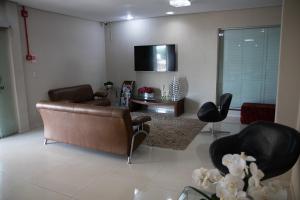 a living room with leather furniture and a tv at Maximus Sottile Hotel in Ji-Paraná
