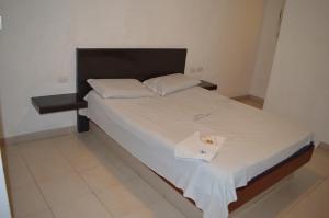 a bed with white sheets and towels on it at Hotel Tiburon in Caracas