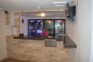 a woman standing behind a bar with a television at Hotel Tiburon in Caracas