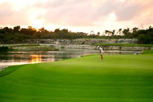 a man standing on a golf green next to a lake at Bahia Principe Luxury Sian Ka´an - Adults Only - All Inclusive in Akumal