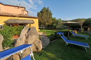 a yard with two blue chairs and an umbrella at Hotel Il Piccolo Golf in Porto Cervo