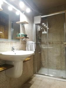 APARTAMENTOS MELCHOR DE LIÑAN في Torrelaguna: حمام مع حوض ودش زجاجي