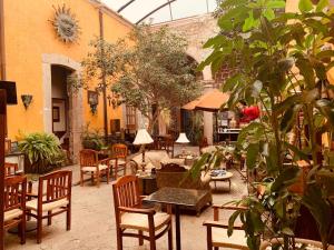 un patio al aire libre con mesas, sillas y plantas en Hotel Casa del Anticuario, en Morelia