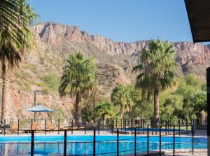 una piscina con palmeras y montañas al fondo en Hotel Valle Grande en San Rafael