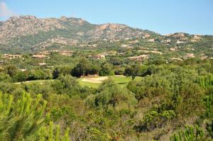 a view of a golf course with mountains in the background at Hotel Il Piccolo Golf in Porto Cervo