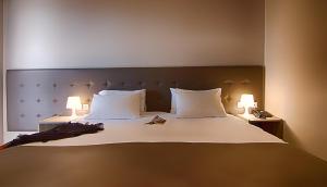 a bedroom with a large bed with two lamps at Galaxy Hotel in Athens