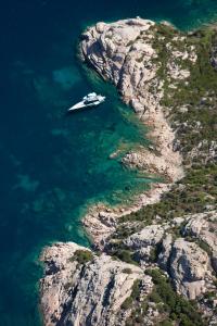 a boat in the water next to a cliff at Hotel Il Piccolo Golf in Porto Cervo