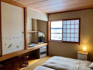 a bedroom with a bed and a desk and a window at Akakura Akarien in Myoko