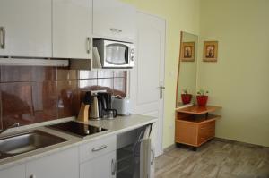 uma cozinha com armários brancos, um lavatório e um micro-ondas em Varga Apartman Hévíz em Hévíz