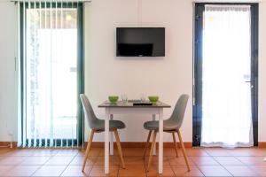 mesa de comedor con sillas y TV en la pared en Les Lofts du Grand Lac de Lozère, en Langogne