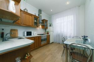 eine Küche mit Holzschränken und einem Tisch mit Stühlen in der Unterkunft квартира in Kiew