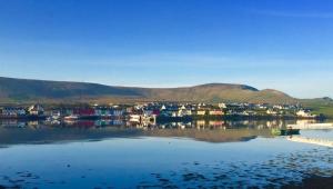 a small town on the water with mountains in the background at Cul Cottage in Valentia Island
