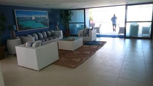ein Wohnzimmer mit weißen Möbeln und einem Mann, der im Hintergrund geht in der Unterkunft Porto Beach Flat in Porto De Galinhas