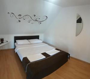 Schlafzimmer mit einem Bett mit weißer Bettwäsche und einem Spiegel in der Unterkunft Pensiunea Denis in Cîrţişoara