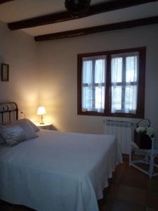 a bedroom with a white bed and a window at La Simona Casa Rural in Perales del Puerto